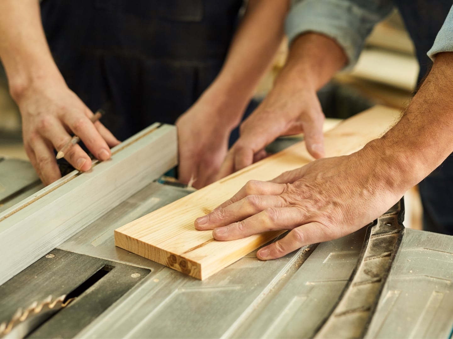 2 men cutting wood on a table saw