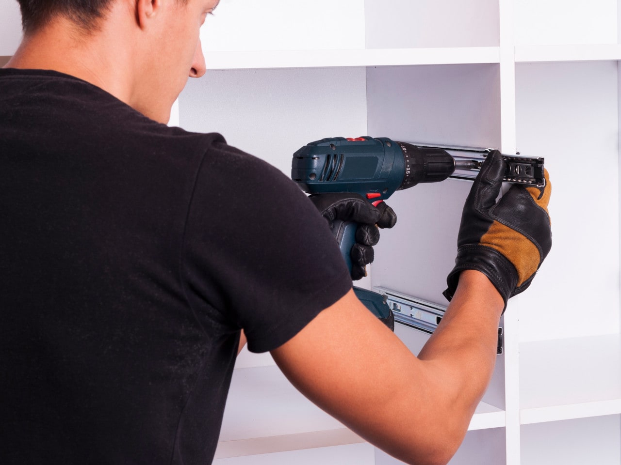 Builder assembling a cabinet with cordless drill